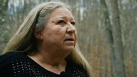 A woman gazes thoughtfully at a photo of herself, reflecting on the memories captured in the image.