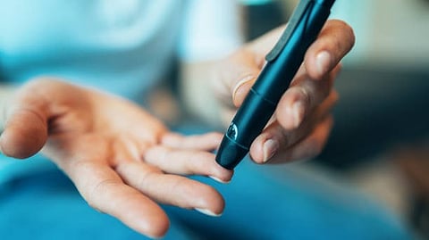 A person holds a cell phone in one hand and a pen in the other, focused on their task.