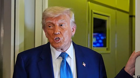 Person in a suit with a blue tie speaking indoors.