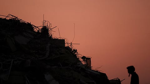 Silhouette of a damaged building with exposed rods against an orange sky.