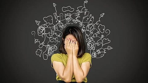 Person covering their face with hands, surrounded by chaotic doodles symbolizing stress, anxiety, or overwhelming thoughts.
