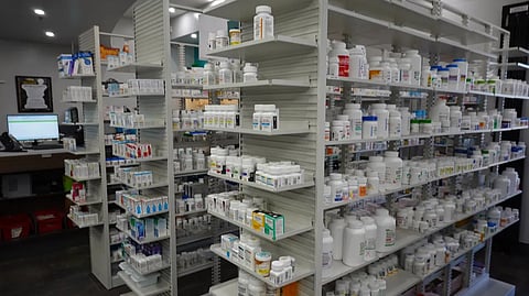 Shelves filled with various medicine boxes and bottles in a pharmacy.