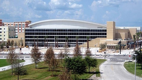 Modern building with a large curved roof and surrounding trees.