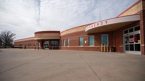 Hospital emergency entrance with a curved brick building and wide driveway.