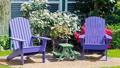 A doctor working on a laptop while holding a clipboard and pen.