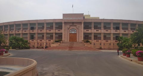 The image shows a large multi-story building with symmetrical architecture and wide steps at the entrance.