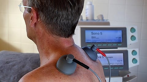 Person recieving neck physiotherapy treatment with electrode pads attached.