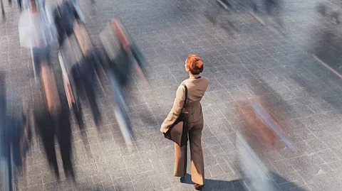 In the image a women is shown walking and the other are blur to show loneliness