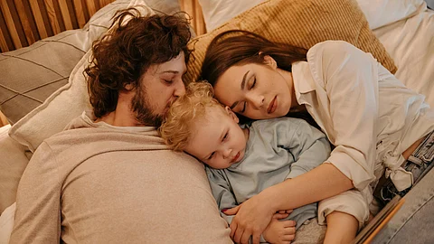 Parents sleeping with their infant child.