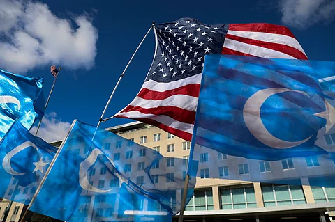 In the image America and Uyghur flags are hoisting in the rally