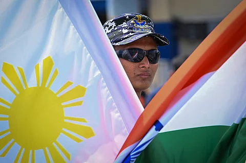 An Indian Navy personnel stands with Philippine and Indian flags at the international port of Manila