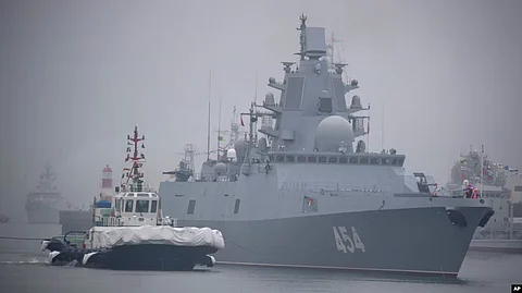 A tugboat escorts the Russian frigate Admiral Gorshkov as it prepares to dock at a port in Qingdao, China