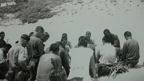 Japanese and American troops kneel in prayer on the island of Aka, June 1945.