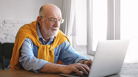 An old man sitting on laptop.