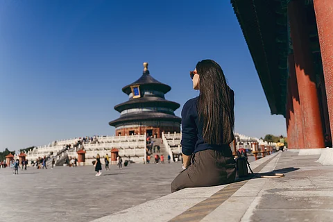 A woman sitting in front of Tibetan monastery.