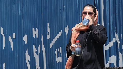 A woman drinks bottled water on a hot day in Tehran.