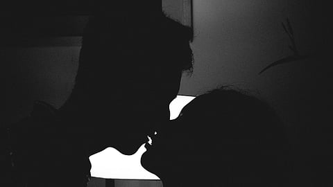 Man and Woman kissing in dark.