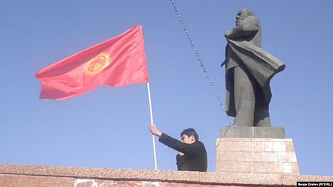 A man waves a Kyrgyz flag next to a statue of Soviet leader Vladimir Lenin in central Osh. City authorities took down the statue in June.