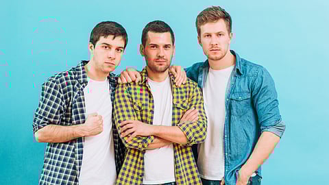 3 guys posing together for pic.