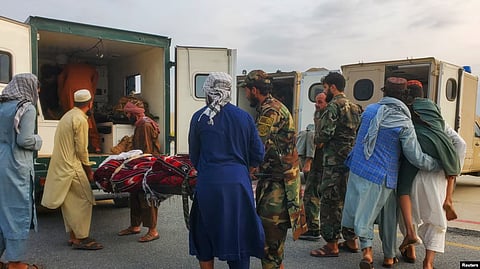 Taliban soldiers and civilians carry earthquake victims to an ambulance at an airport in Jalalabad
