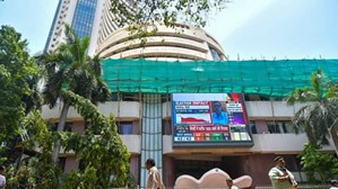 Mumbai: People walk past a screen showing stock market goes down outside BSE building at Dalal Street after the counting of votes for Lok Sabha polls, in Mumbai on Tuesday, June 4, 2024.
