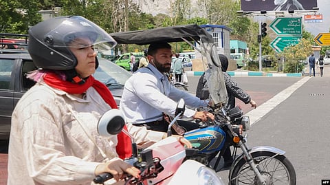 A man and a woman ride their motorcycles in central Tehran.