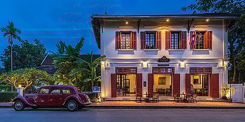 100-year-old Hotel 3 Nagas with an old red Citroën Model 11 Family version (1952) at blue hour in Luang Prabang, Laos.