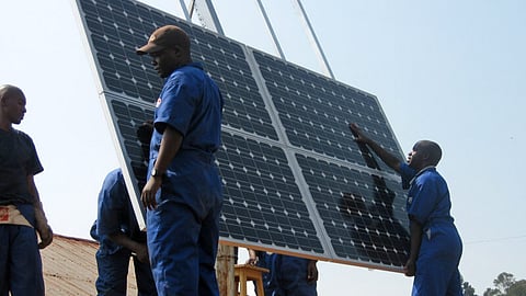 Workers install solar panels at health clinics in Rwanda.