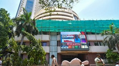 Mumbai: People walk past a screen showing stock market goes down outside BSE building at Dalal Street after the counting of votes for Lok Sabha polls, in Mumbai on Tuesday, June 4, 2024