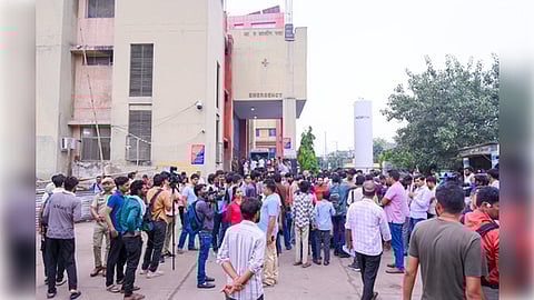 A crowd of people standing in line outside a multi- story building.