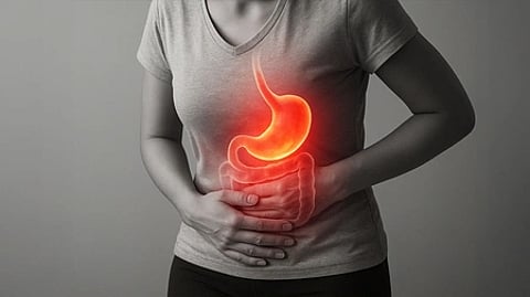 A grayscale image shows a person clutching their stomach, highlighting a glowing, red illustration of a stomach area, symbolizing pain or discomfort.