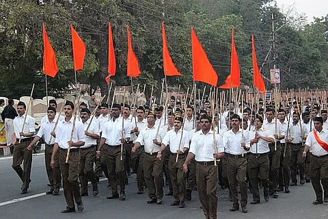An RSS march in Bhopal, with members raising saffron flags.