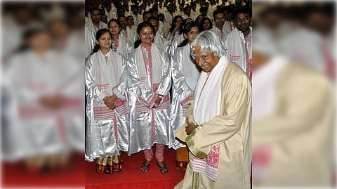 APJ Abdul Kalam in a ceremonial robe stands smiling, interacting with graduates in silver gowns at a convocation, exuding a joyful and formal atmosphere.