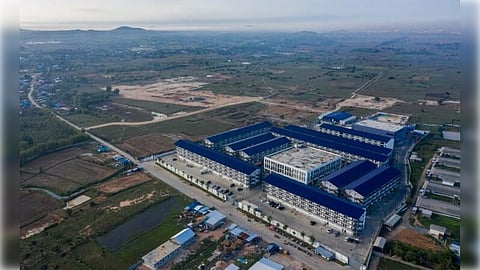 Drone footage of an alleged scamming compound in Cambodia with high perimeter walls, security cameras, and security guards.