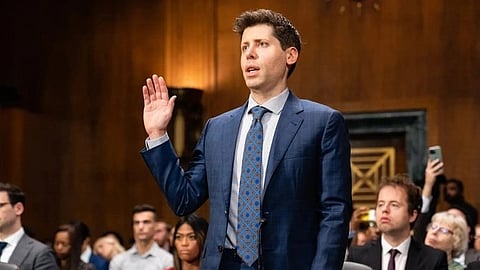 Image of OpenAI CEO of ChatGPT Sam Altman raising his hand in a blue formal suit.