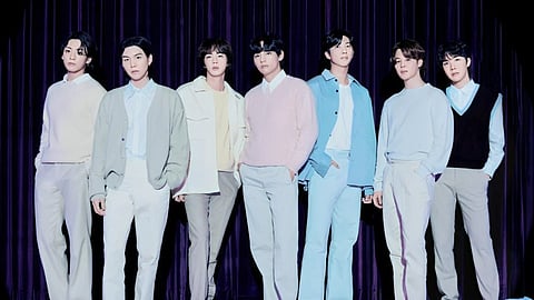 BTS members posing in front of camera. Everone is wearing fashionable clothes