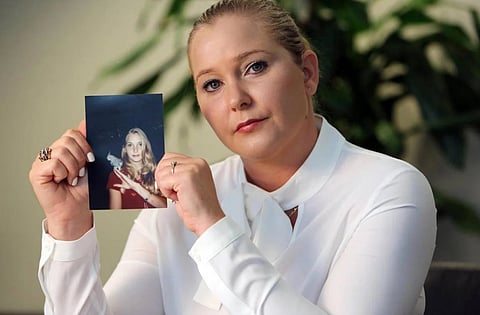 image of Epstein survivor Virginia Giuffre holding a photograph of herself when she was young girl