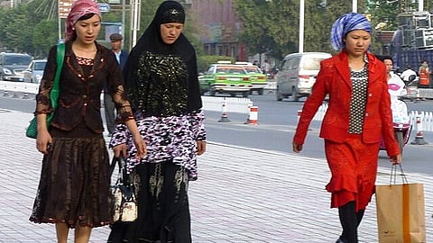Uyghur women on their way to work. They are walking in the sidewalk