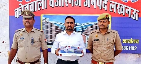 Image of UP's fake IAS officer Saurabh Tripathi with two UP police officer with a poster in the back.