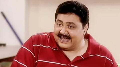 In the image Satish Shah is smiling. He is wearing a red t-shirt with white stripes