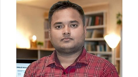 Ujawal Jha posing in front of camera wearing checked red shirt