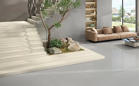 Image of a living room which has a sofa plants and staircase with tiles.