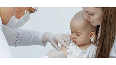 A doctor vaccinating a child by inserting syringe. The mother is holding her child.