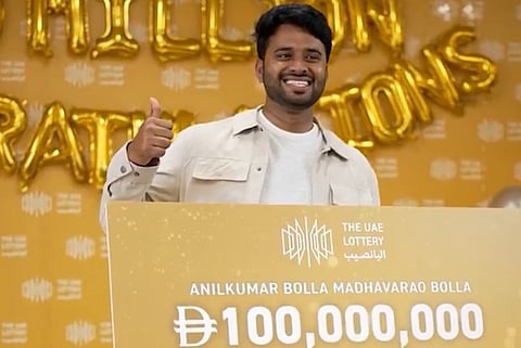 image of Anilkumar Bolla from Andhra Pradesh holding a Dh 100 million check in his hand in the 23rd Lucky Day Draw.