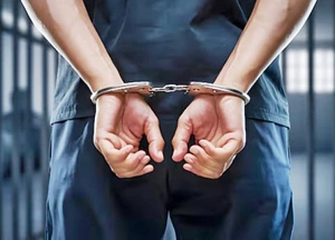 In the image a man is shown walking in blue uniform with his handcuffed hand. Representational image