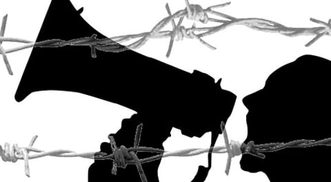 In the image a black shadow of someone is shown speaking in a announcer mic and above that is  barricades