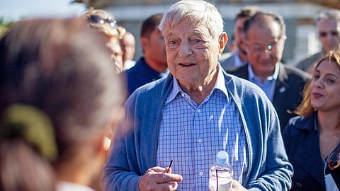 In the image open society founder George Soros is shown wearing a shirt and outer