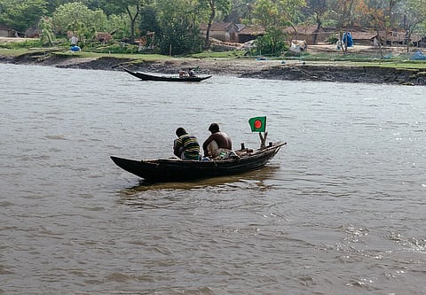 Two Bangladeshi fisherman tending their nets on their country boat in Ichamati river. The river Bank is Sripur town in Khulna division, Bangladesh.