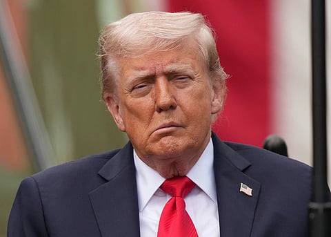 Close up shot of Donald Trump in his classic dark blue suit and red tie. he is wearing a tiny badge of the national flag of United States of America.