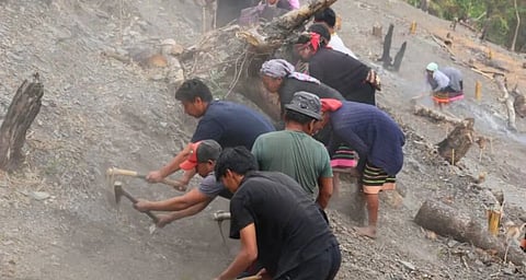 Farmers digging into a barren hillside, preparing the land for farming.